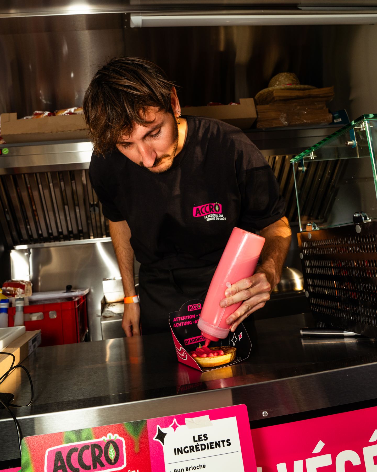 Sauce kommt auf einen Burger, auf der Edelstahl-Arbeitsfläche eines Food Trucks