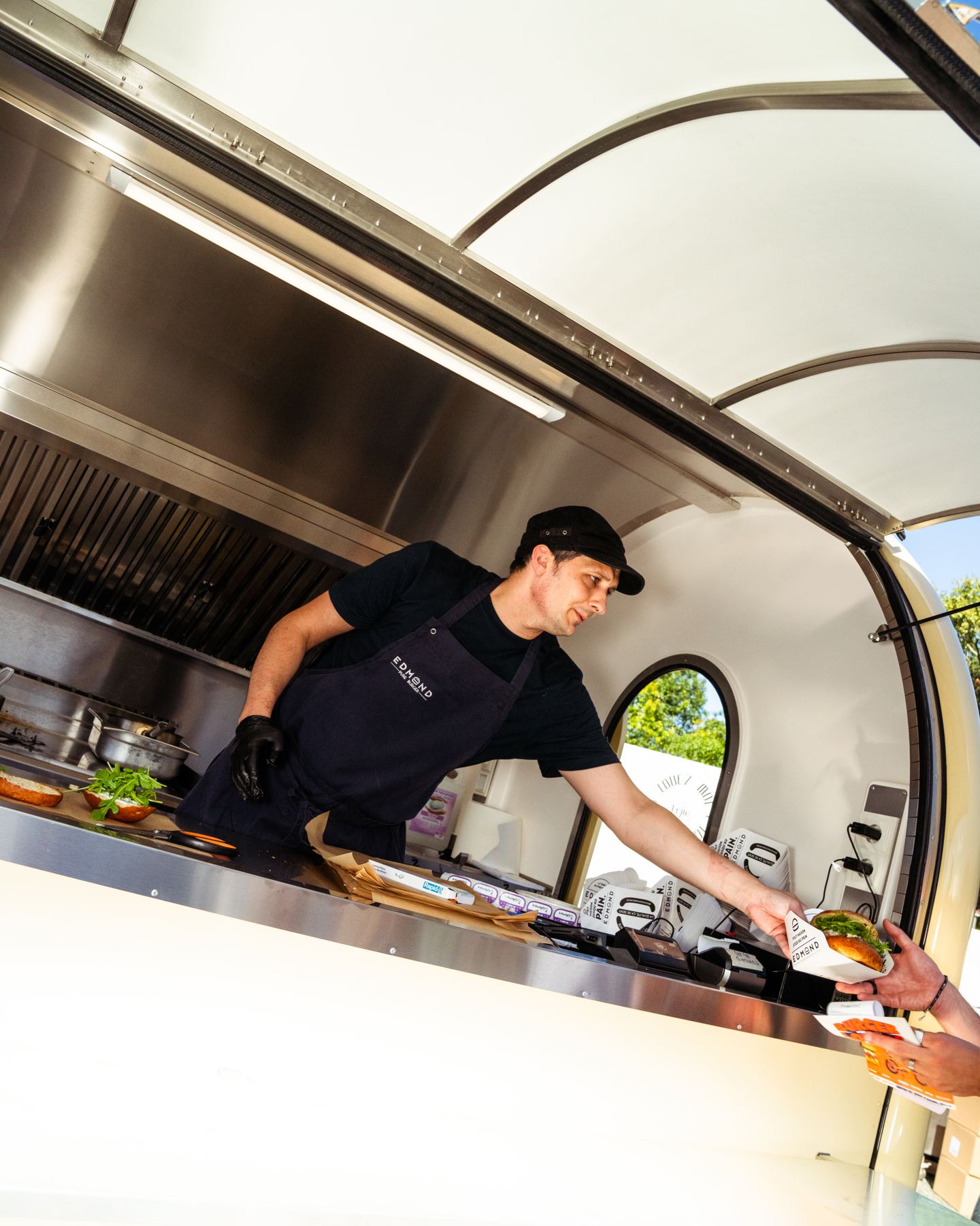 Ein Koch bedient einen Kunden aus seinem Food-Truck-Anhänger