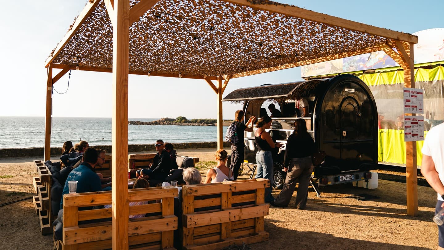 Food-Truck-Anhänger am Strand, Gäste an Tischen unter der Pergola